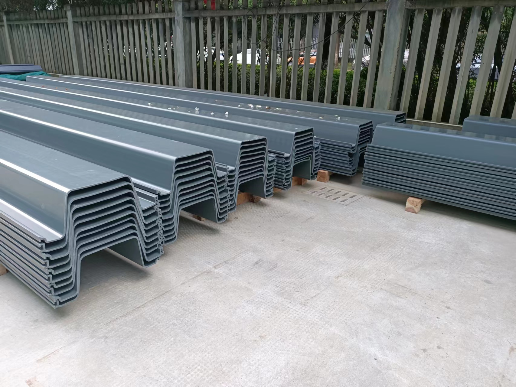 Stacked gray Z-profile PVC sheet piles showing the actual profile shape and interlocking edges.