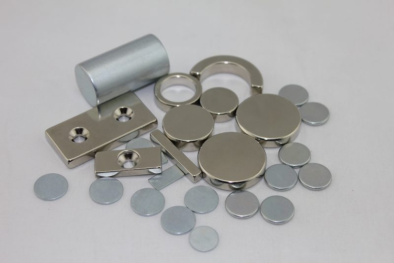 Black epoxy-coated neodymium magnets in block, disc, ring and arc shapes on a white background. Black epoxy-coated neodymium magnets in block, disc, ring and arc shapes on a white background.