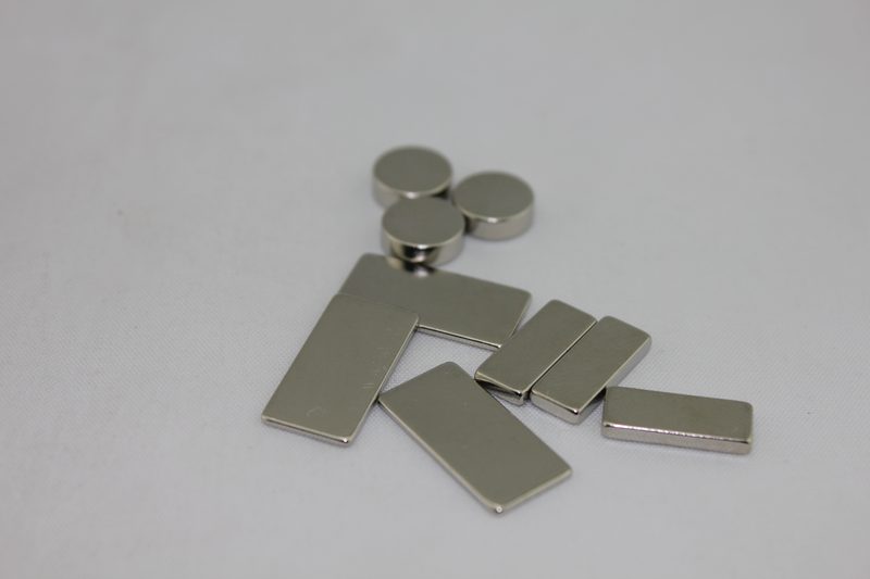 Black epoxy-coated neodymium magnets in block, disc, ring and arc shapes on a white background. Black epoxy-coated neodymium magnets in block, disc, ring and arc shapes on a white background.