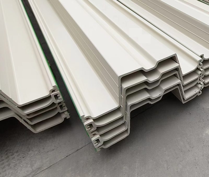 Gray PVC sheet pile profiles stored in outdoor racks, with profile ends and interlocks visible.