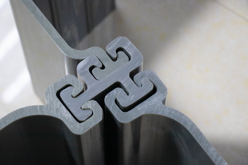 Light-colored PVC sheet pile profiles stacked in a clean bundle with the interlocking profile ends visible.