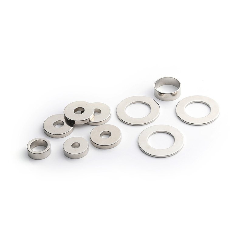 Three nickel-plated neodymium ring magnets arranged separately on a clean white background.