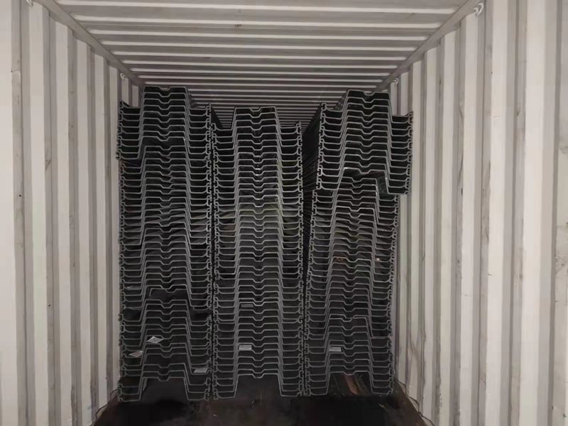 Gray PVC sheet pile profiles stacked on timber spacers with profile ends and interlocks visible.